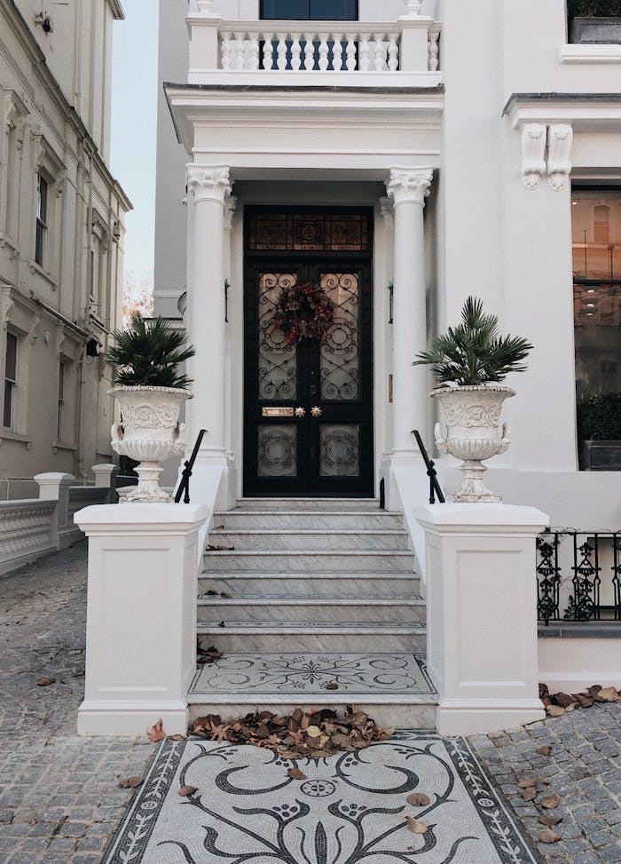 Wide-angle view of a classic luxury townhouse entrance in London featuring ornate columns and potted plants.